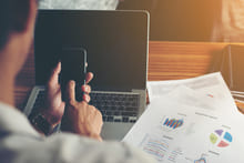 Businessman hands using cell phone with financial report  at off